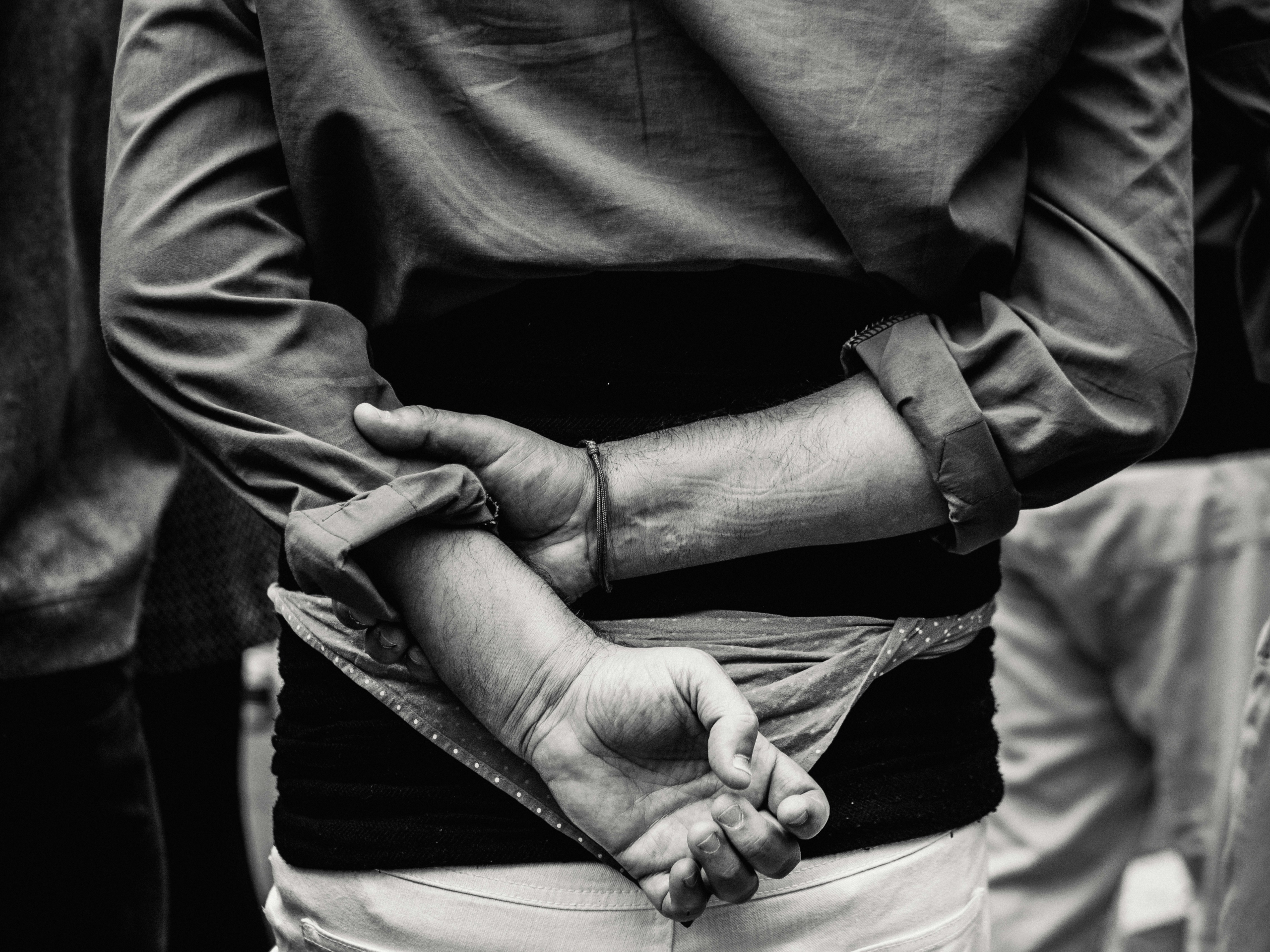 Black and white picture of man handcuffed from behind